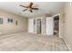 Large bedroom with neutral carpet and a ceiling fan, showcasing multiple entry doors at 5472 Ives Nw St, Concord, NC 28027