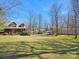 Expansive front yard showcasing lush green grass and mature trees surrounding the charming log home at 5981 Johnson Rd, Lake Wylie, SC 29710