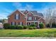 Charming two-story red brick home with well-manicured landscaping and a welcoming front porch with white columns at 714 Castlestone Ln, Matthews, NC 28104