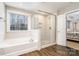 Bright bathroom featuring a soaking tub, a glass enclosed shower, and wood look tile flooring at 114 Tomahawk Dr, Mooresville, NC 28117