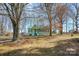 Quaint home featuring a green roof and shutters nestled between trees and a lawn covered with fallen leaves at 120 Benfield Rd, Statesville, NC 28677