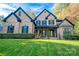 Beautiful brick two-story home featuring a manicured lawn and mature landscaping with green grass at 4268 Rustling Woods Dr, Denver, NC 28037