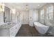 Bright bathroom featuring a soaking tub under a window, dual sinks, and modern gold lighting at 5026 Ohm Ln, Charlotte, NC 28270
