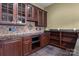Close-up of wet bar with dark wood cabinets, tiled backsplash, granite counters, microwave, and open shelves at 8034 Bay Pointe Dr, Denver, NC 28037