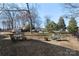 Expansive backyard with mature trees, patio set, and a fire pit under a blue sky at 1016 Helms Rd, Charlotte, NC 28214