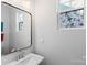 Clean bathroom featuring a pedestal sink, decorative mirror, and a unique stained glass window at 1016 Helms Rd, Charlotte, NC 28214