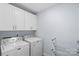 Well-lit laundry room with white cabinets, a washer, a dryer, and a folding rack at 1016 Helms Rd, Charlotte, NC 28214