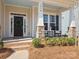 Inviting front porch with rocking chairs, decorative wreath, and stone pillar accents for a cozy welcome at 1016 Hickory Pine Rd, Waxhaw, NC 28173