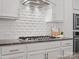This kitchen features a stainless cooktop with a designer hood and a white subway tile backsplash at 1016 Hickory Pine Rd, Waxhaw, NC 28173