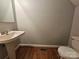 Cozy half-bathroom with pedestal sink and wood flooring. Great for guests at 1516 Plantation Trl, Gastonia, NC 28056