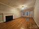 Open living room features a fireplace, hardwood floors, ceiling fan, and large windows for natural light at 1516 Plantation Trl, Gastonia, NC 28056
