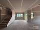 Unfinished living room with staircase and windows. 