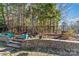 Landscaped backyard featuring a stone retaining wall, stairs, and a black metal fence backing up to a wooded area at 2439 Bergamot St, Fort Mill, SC 29708