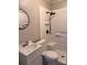 Bathroom featuring a white tiled shower with black fixtures, a modern sink and vanity, and a round mirror at 2507 Florida Ave, Kannapolis, NC 28083