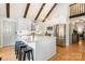 Well-lit kitchen with white cabinets, a central island with seating, and stainless steel appliances, enhanced by wood beams at 353 Whippoorwill Rd, Mooresville, NC 28117