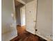 Hallway with wood floors, damaged walls, and doorways leading to other rooms in the house at 6705 Edenwood Pl, Charlotte, NC 28212