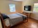 Well-lit bedroom with hardwood floors, a tv and two windows providing ample sunlight at 7107 Wilson Grove Rd, Mint Hill, NC 28227