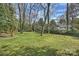 Large backyard with mature trees, green lawn, and glimpses of the house, offering a private outdoor space at 830 Jefferson Dr, Charlotte, NC 28270