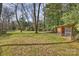 Spacious backyard featuring a well-maintained lawn, mature trees, and a chicken coop or small animal enclosure at 830 Jefferson Dr, Charlotte, NC 28270