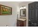 Cozy powder room with hardwood vanity, granite countertop, mirror, and decorative art at 830 Jefferson Dr, Charlotte, NC 28270