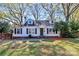 Charming cottage-style home featuring white siding, black shutters, dormer windows and a landscaped front yard at 1101 Lancaster Ave, Monroe, NC 28112