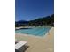Community pool featuring a blue sunshade, lounge seating, and mature trees at 121 Edgehill Ct, Troutman, NC 28166