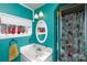 This is a full bathroom with a white sink, oval mirror, decorative trees on the window sill, and teal walls at 206 Mcconnell St, Clover, SC 29710