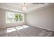 Bright bedroom featuring large window, tray ceiling, modern light fixture, and neutral carpet at 2216 Camber Dr # Cwo0074, Gastonia, NC 28054