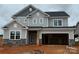 Two-story home featuring gray siding, stone accents, a two-car garage, and architectural roof details at 2216 Camber Dr # Cwo0074, Gastonia, NC 28054