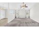 Carpeted living room featuring a ceiling fan and windows, leading to a dining area with a chandelier at 414 Glencroft Dr, Wingate, NC 28174