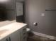 A bathroom with white vanity, sink, mirror and gray walls, featuring a toilet and medicine cabinet at 1220 Avalon Pl, Matthews, NC 28104