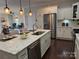 Bright, open kitchen features stainless appliances, white cabinetry, and island with stone countertop and sink at 1220 Avalon Pl, Matthews, NC 28104