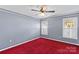 This bedroom is bright and airy, with plush red carpet and ceiling fan at 130 Ketchie Dr, Mooresville, NC 28115