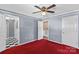 This bedroom features a ceiling fan, plush red carpet, and natural light at 130 Ketchie Dr, Mooresville, NC 28115