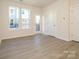 The bedroom with wood-look flooring, large windows, and a white door leads to a balcony at 1307 Cerium Way, Charlotte, NC 28211