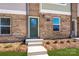 Close-up of a townhome's entry with a green door, brick facade, and concrete steps leading to a cozy home at 1307 Cerium Way, Charlotte, NC 28211