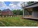 Large backyard with lush lawn, featuring a covered patio and a neighboring brick home at 144 Sardis Ln, Charlotte, NC 28270