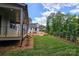 View of the back porch with steps leading to a large grassy area with trees in the background at 144 Sardis Ln, Charlotte, NC 28270