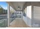 Covered porch with ceiling fan, natural wood floors, metal railings, and wooded view at 144 Sardis Ln, Charlotte, NC 28270