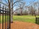 Landscaped backyard with wrought iron fence, mature trees and a view of lawn at 2027 Meadowood Ln, Charlotte, NC 28211