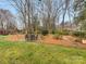 Backyard featuring a stone patio with outdoor furniture amidst trees, landscaping, and lawn at 2027 Meadowood Ln, Charlotte, NC 28211