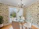Bright dining area featuring a glass table, white chairs, and botanical wallpaper, illuminated by a stylish chandelier at 2027 Meadowood Ln, Charlotte, NC 28211