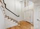 Bright foyer with hardwood floors, elegant staircase with black handrail, and a paneled front door at 2027 Meadowood Ln, Charlotte, NC 28211