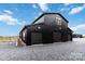 Modern barn style home with black siding, multiple garage doors, and a gravel driveway at 2288 Boheler Rd, Clover, SC 29710
