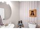A contemporary bathroom featuring a stylish round mirror, decorative wallpaper, and modern fixtures at 247 Reese Wilson Rd, Belmont, NC 28012