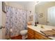 Bathroom features a shower with patterned curtain, a vanity, and a decorative mirror at 4642 Willow Glen Rd, Harrisburg, NC 28075