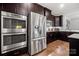 Gourmet kitchen featuring a double oven, stainless steel refrigerator, and dark wood cabinetry at 6112 Canyon Trl, Denver, NC 28037
