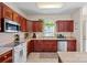 Well-lit kitchen with dark wood cabinetry, stainless steel appliances, and a charming window at 653 Camrose Ne Cir, Concord, NC 28025