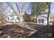 Spacious backyard with a paved driveway leading to a garage and a fire pit seating area, framed by mature trees at 85 Grove Nw Ave, Concord, NC 28025