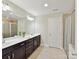 Bright bathroom featuring double sink vanity, large mirror, and walk-in shower, offering modern convenience at 16404 Mckee Ridge Dr, Charlotte, NC 28278